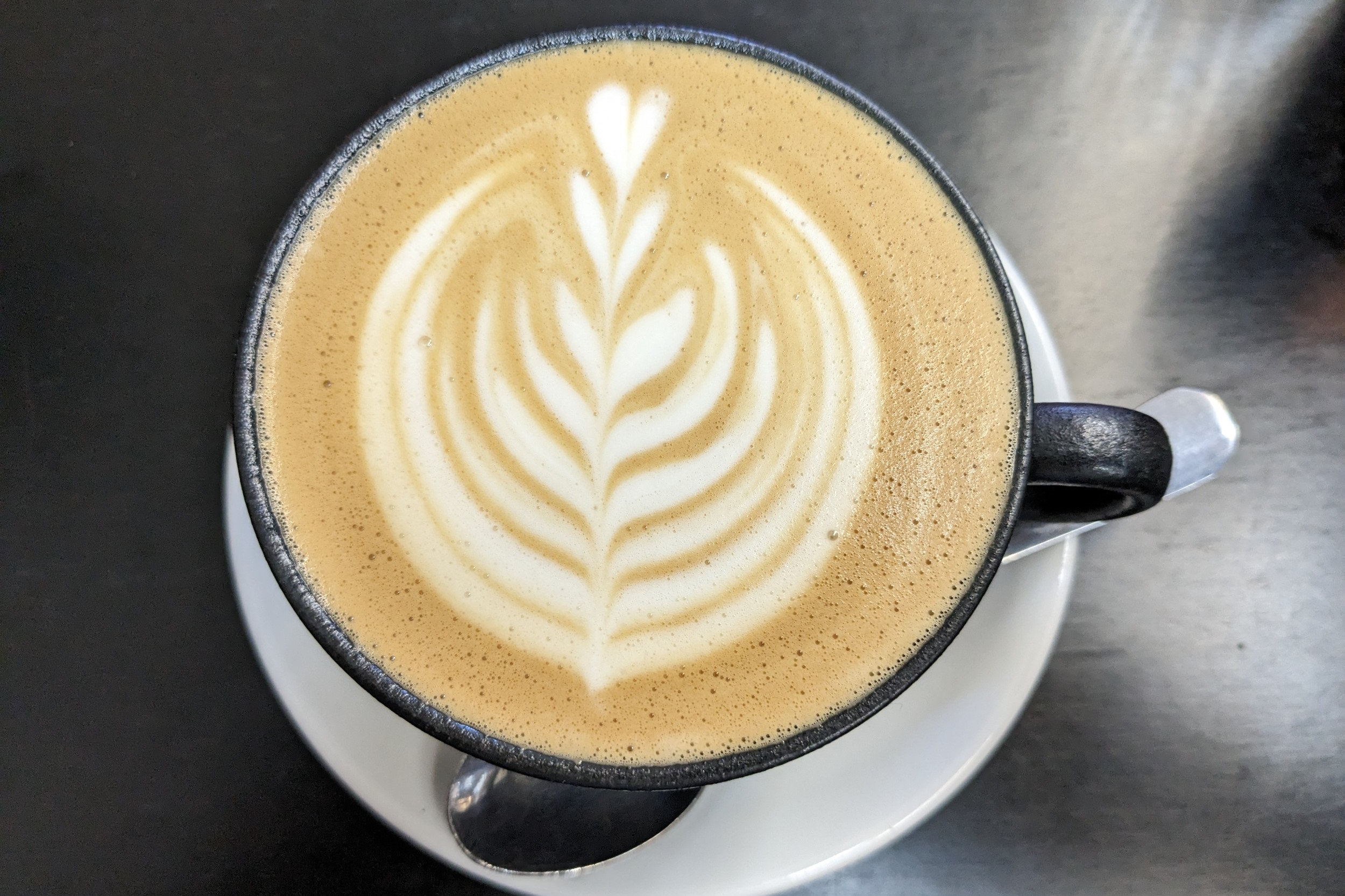 Top-down view of flat white coffee with latte art on metal table