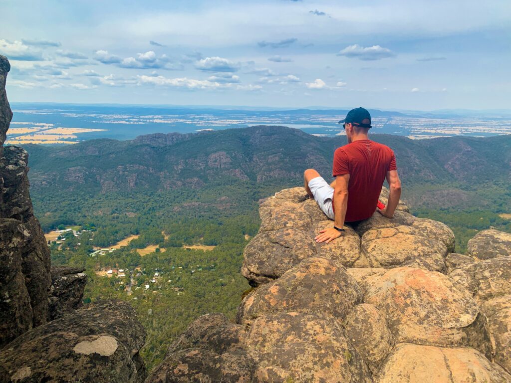 Man sitting at a viewpoint on rocky outcrop, looking towards halls gap, with plains in the distance