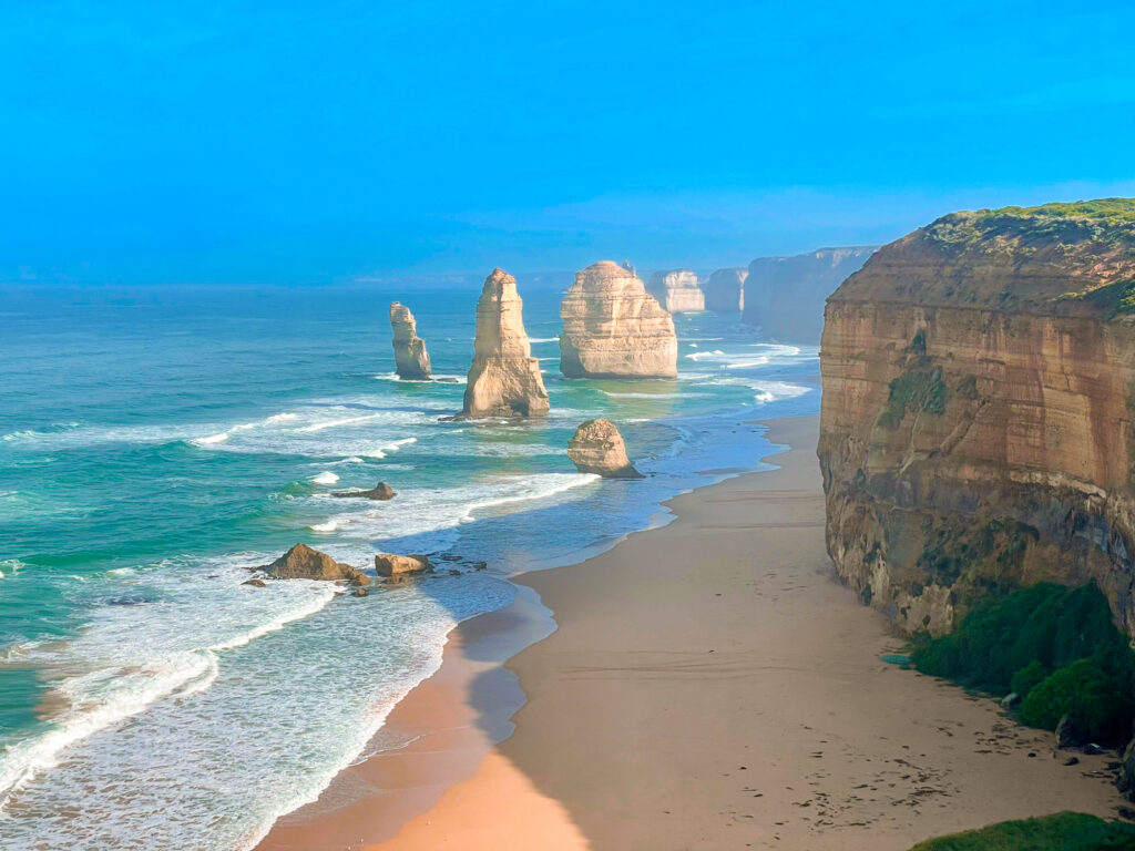 12 Apostles limestone rock formations in the ocean just off the beach, beside cliffs