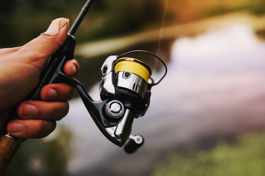 Closeup of fishing rod and reel being held in hand with blurred river in the background