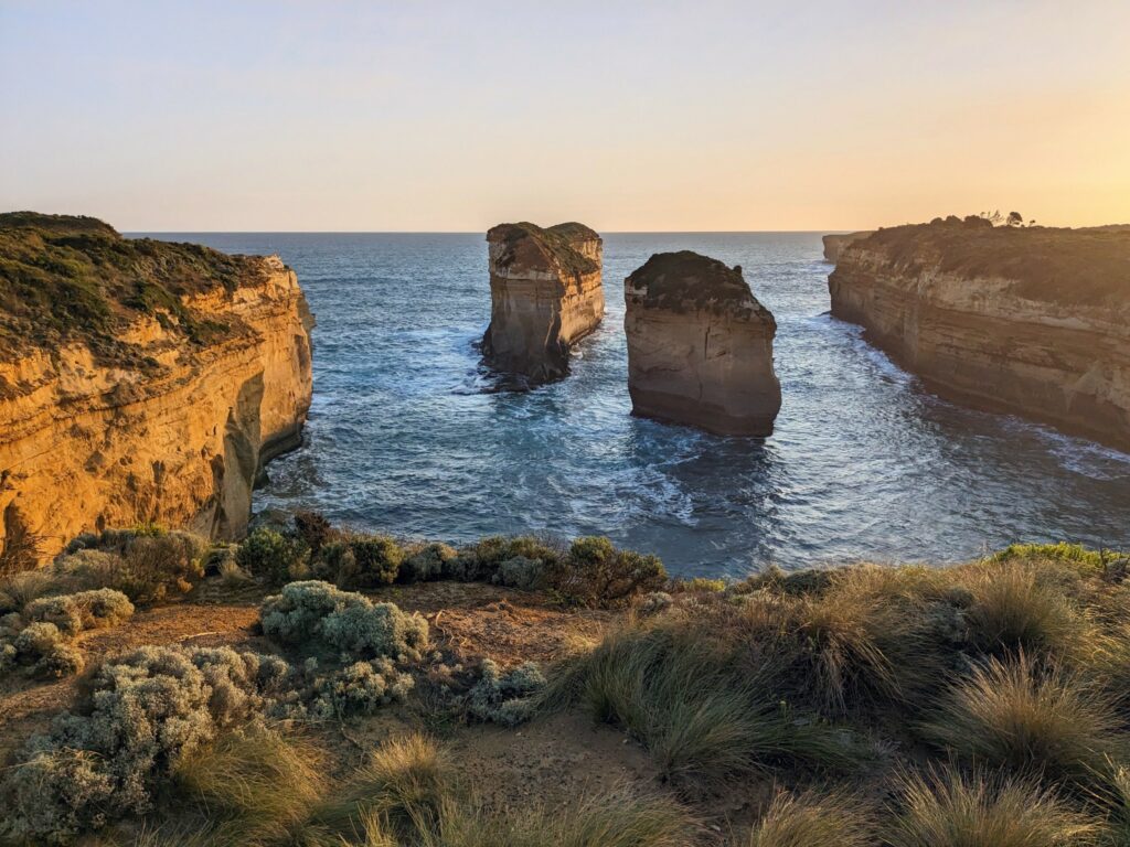 Two limestone rock formations in a small bay at sunset, with cliffs on either side