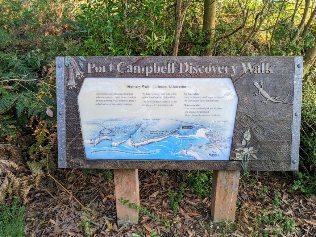 Wooden sign with information about the Port Campbell Discovery Walk, decorated with boot prints and local flora and fauna around the edges