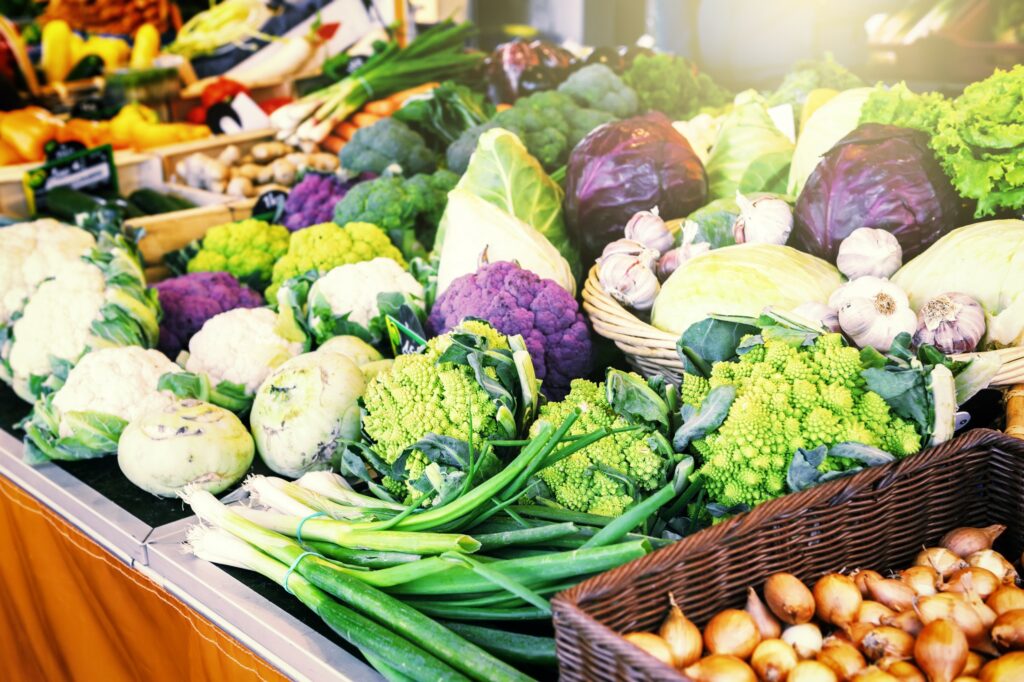 Range of produce at a market stall, including cabbage, cauliflower, garlic, and others.