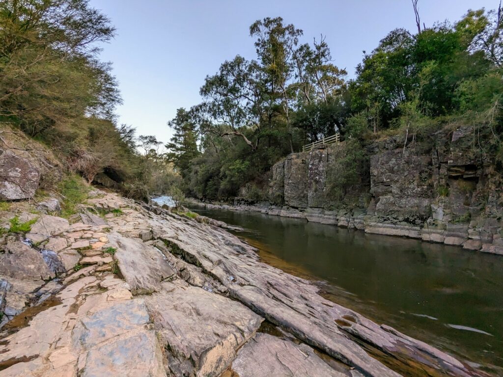 Rocky section of trail on Bright Canyon Walk, with river alongside and higher rocky bank on the other side.