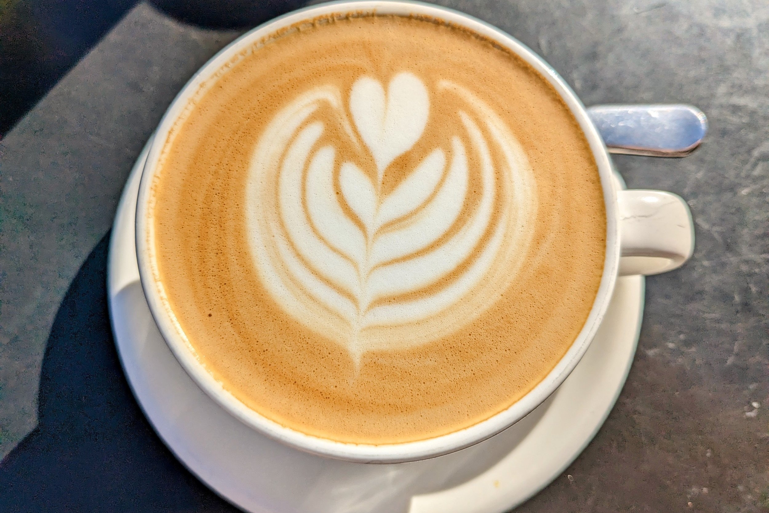 Overhead view of coffee cup with latte art on a metal table