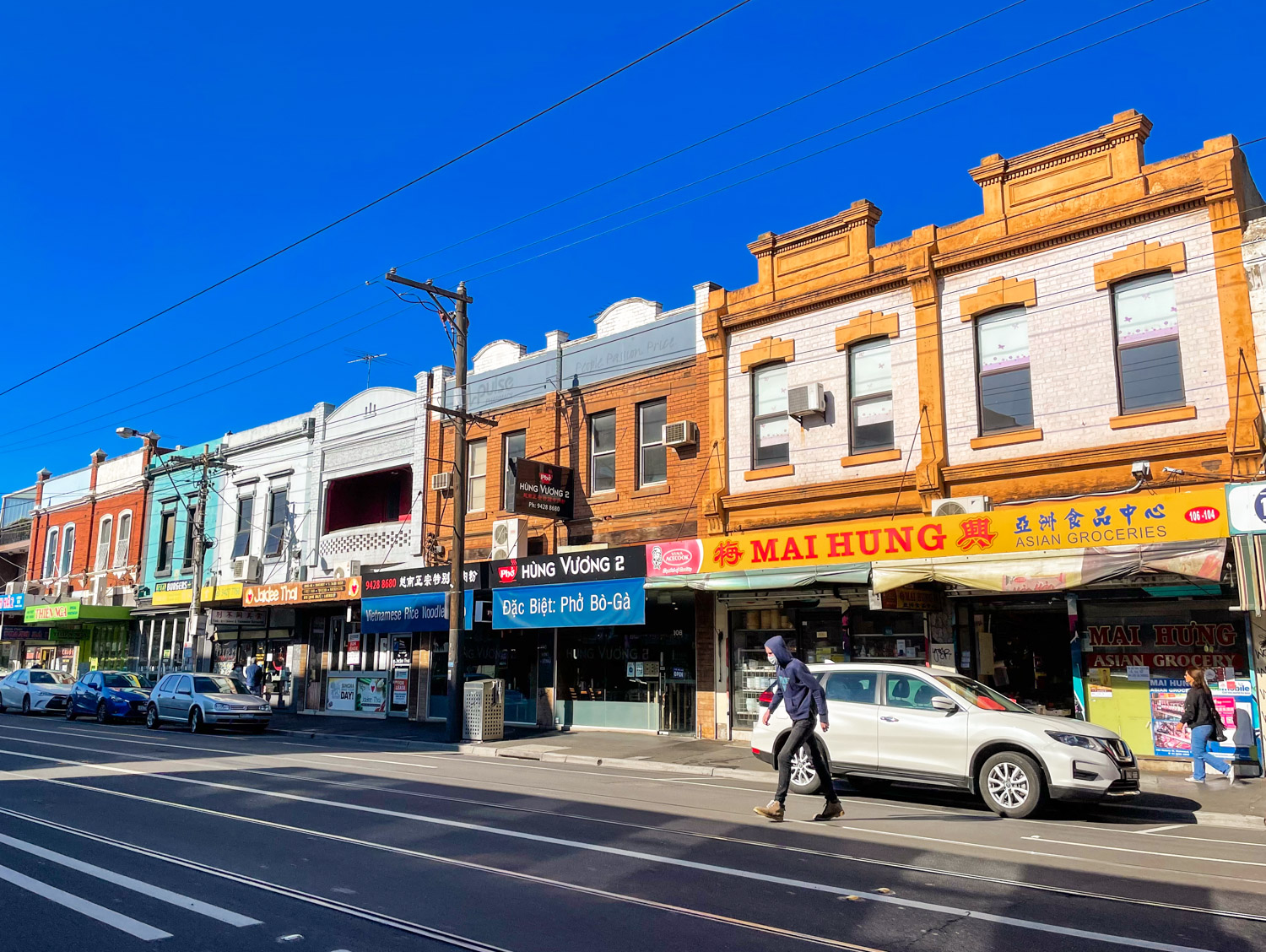 A series of colourful Vietnamese restaurants and supermarkets lining Richmond's Victoria Street on a sunny day in spring. 