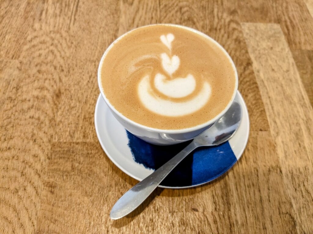Overhead view of flat white on a blue and white saucer, sitting on a wooden table