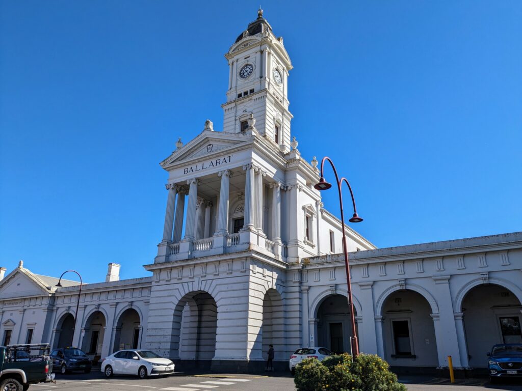 Grand exterior of Ballarat train station with white columns and clock tower. 